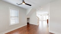 Located at 2001 Lynn St in Louisville, KY, this two-story, two-bedroom, three-bathroom home offers a well-designed layout across two thoughtfully proportioned floors. The main level welcomes you with rich, dark hardwood flooring that flows through a bright living area and into an open-concept kitchen. The kitchen is outfitted with warm wood cabinetry, granite countertops, stainless steel appliances, and a central island illuminated by pendant lighting — ideal for both cooking and entertaining. A hallway with light hardwood floors connects key areas of the main level, including a dedicated laundry room with a stacked washer and dryer unit. The main level also features a bathroom with classic white subway tile surrounding the tub-shower combination. Upstairs, the home transitions to plush carpeting in both bedrooms. The spacious primary bedroom includes a ceiling fan, multiple windows for natural light, a walk-in closet, and an en-suite bathroom. The second bedroom is generously sized with wide windows offering neighborhood views and its own ceiling fan. Throughout the home, neutral wall tones, clean white trim, and consistent finishes create a cohesive, modern aesthetic. The two-story staircase with a clean white banister serves as a functional centerpiece tying both levels together.