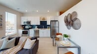 This thoughtfully designed single-floor residence offers a seamless blend of modern aesthetics and practical living. The open-concept layout connects the kitchen, dining, and living areas into one cohesive, light-filled space. The kitchen is outfitted with stainless steel appliances, crisp white shaker cabinetry, quartz countertops, a stainless undermount sink, and a striking navy geometric tile backsplash that adds a bold design accent. A window above the counter draws in natural light. The dining area sits adjacent to the kitchen and flows naturally into the living room, which features light wood-style flooring, recessed lighting, and a large sliding glass door that opens to a private balcony with open city views — a standout feature of the space. The bedroom offers a quieter retreat with carpeted flooring, clean white walls, and ample space. The full bathroom is finished with light wood-style flooring, a white vanity with quartz countertop and under-mount sink, a large mirror, and a tub-shower combination accented by white subway tile and a bold navy herringbone tile inset. A hallway connecting the rooms features in-unit stacked laundry and is adorned with framed artwork, completing the polished, modern feel throughout.