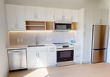 This efficiently designed 440 square foot studio apartment in Fayetteville, Arkansas, offers a modern living space on a single floor. The open-concept layout maximizes the use of space, seamlessly blending the living, sleeping, and dining areas. The kitchen is equipped with contemporary white cabinetry, stainless steel appliances including a microwave and refrigerator, and under-cabinet lighting, creating a sleek and functional cooking space.

Light wood-tone flooring extends throughout the apartment, complementing the crisp white walls and creating a bright, airy atmosphere. Large windows and a sliding glass door leading to a private balcony flood the space with natural light, offering views of the surrounding area and expanding the living space outdoors.

The bathroom features clean lines and modern fixtures, with a combination of white and light-colored tiles. Storage solutions are integrated throughout, including built-in shelving near the entry. The apartment's design emphasizes simplicity and functionality, with paneled doors and recessed lighting contributing to the overall contemporary aesthetic. This studio provides an ideal living space for those seeking a compact yet stylish urban dwelling.