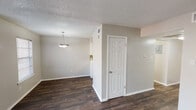 Located at 944 Simpson Terr in Bedford, Texas, this two-story home presents a clean, neutral aesthetic throughout its well-organized layout. The main living area features rich, dark hardwood-style flooring that extends through the open-concept space, complemented by soft gray walls and white trim. A ceiling fan with integrated lighting anchors the living room, which receives natural light through a window fitted with horizontal blinds and a sliding glass door dressed in vertical blinds.

The dining area connects seamlessly to the living space and is highlighted by a pendant light fixture overhead. The kitchen is equipped with white cabinetry, black electric coil range, over-the-range microwave, and dark hardwood-style flooring that carries through from the main living areas. A window provides additional natural light, and the electrical panel is conveniently accessible nearby. A staircase leads to the upper level.

Upstairs, the bedrooms feature neutral carpet, ceiling fans with lighting, and windows that allow natural light to filter in. Closet access is provided through six-panel doors. The bathrooms offer white vanities with speckled countertops, brushed nickel fixtures, framed mirrors with vanity lighting, and a tub-shower combination. Textured ceilings are present throughout the home.