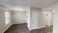 Located at 944 Simpson Terr in Bedford, Texas, this two-story home presents a clean, neutral aesthetic throughout its well-organized layout. The main living area features rich, dark hardwood-style flooring that extends through the open-concept space, complemented by soft gray walls and white trim. A ceiling fan with integrated lighting anchors the living room, which receives natural light through a window fitted with horizontal blinds and a sliding glass door dressed in vertical blinds.

The dining area connects seamlessly to the living space and is highlighted by a pendant light fixture overhead. The kitchen is equipped with white cabinetry, black electric coil range, over-the-range microwave, and dark hardwood-style flooring that carries through from the main living areas. A window provides additional natural light, and the electrical panel is conveniently accessible nearby. A staircase leads to the upper level.

Upstairs, the bedrooms feature neutral carpet, ceiling fans with lighting, and windows that allow natural light to filter in. Closet access is provided through six-panel doors. The bathrooms offer white vanities with speckled countertops, brushed nickel fixtures, framed mirrors with vanity lighting, and a tub-shower combination. Textured ceilings are present throughout the home.