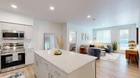 This well-appointed 2-bedroom, 4-bathroom residence offers a thoughtfully designed single-floor layout that maximizes both comfort and functionality. Light hardwood flooring flows consistently throughout the space, creating a cohesive and airy aesthetic.

The open-concept living and kitchen area serves as the heart of the home. The kitchen is outfitted with stainless steel appliances, including a refrigerator, range, and microwave, complemented by white shaker-style cabinetry and a granite-topped island that provides additional prep and seating space. A dedicated entryway with a tufted bench and bold wall art creates a welcoming transition into the home.

The living room is bright and inviting, featuring large windows and a glass door that floods the space with natural light and provides direct access to an outdoor area. Recessed lighting adds to the clean, modern ambiance.

The primary bedroom is a comfortable retreat, featuring a walk-in closet, a large window with outdoor views, and its own dedicated bathroom. The second bedroom mirrors this bright, well-proportioned character. All four bathrooms maintain a consistent modern design with white vanities featuring brushed nickel hardware, matching cabinetry, and light hardwood-style flooring. The overall design is clean, minimalist, and move-in ready.