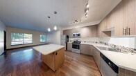 Located at 580 8th Ave NE in Issaquah, WA, this well-appointed 2-bedroom, 2-bathroom residence offers a thoughtfully designed single-floor layout with a generous overall footprint. The open-concept kitchen and living area serves as the heart of the home, featuring warm hardwood flooring that flows throughout the main living spaces. The kitchen is equipped with stainless steel appliances—including a side-by-side refrigerator with ice maker, a range, and a dishwasher—complemented by modern flat-front cabinetry with a mosaic tile backsplash and track lighting overhead. Large windows in the living area flood the space with natural light and offer pleasant outdoor views of the surrounding Issaquah neighborhood. Both bedrooms are carpeted for comfort, with the primary bedroom offering a well-proportioned layout and access to closet storage. Four closets in total provide ample organization throughout the unit. The bathrooms feature wood-toned vanities with stone-finish countertops and large mirrors. A dedicated laundry area and a private balcony add everyday convenience and outdoor access. Hallways connect the rooms with ease, and the clean, neutral color palette throughout creates a bright and welcoming ambiance.