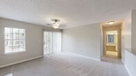 Located at 1015 King George Blvd in Savannah, GA, this single-floor residence offers a well-organized layout that makes efficient use of its space. The combined kitchen and living room forms the heart of the home, with the living area finished in plush wall-to-wall carpeting and illuminated by a ceiling fan light fixture. A sliding glass door flanked by vertical blinds, along with an additional window, fills the room with natural light and provides outdoor views. A standout feature of the living area is the tile-surround fireplace flanked by two sets of built-in shelving units — ideal for display and storage. The galley-style kitchen is outfitted with white cabinetry, dark granite-style countertops, tile flooring, and black appliances including a refrigerator, range, and microwave. The spacious primary bedroom is carpeted and features its own ceiling light fixture along with access to a dedicated closet, offering generous personal storage. Neutral gray walls and textured ceilings are consistent throughout the home, contributing to a clean, understated aesthetic. The overall ambiance is bright, functional, and comfortable — well-suited for everyday living in the Savannah area.