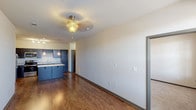This single-floor residence is thoughtfully designed with a functional, open layout that connects the living and kitchen areas seamlessly. The kitchen serves as a central highlight, featuring dark espresso cabinetry paired with light granite countertops, a large central island ideal for dining or food preparation, and a full suite of stainless steel appliances including a refrigerator, electric range, microwave, and dishwasher. A built-in wine rack adds a distinctive touch, while pendant lighting over the island and track lighting above provide ample illumination. Rich hardwood-style flooring flows throughout the kitchen and living areas, complementing the neutral wall tones.

The living area is open and bright, benefiting from natural light through sizable windows and a ceiling fan fixture overhead. The bedrooms are carpeted for added comfort, each featuring ceiling fans and generous wall space. One bedroom includes multiple windows with blinds, allowing for natural light and outdoor views.

The bathroom is well-equipped with a granite-topped vanity, a full soaking tub with shower surround, and coordinating dark cabinetry. Throughout the unit, dark-trimmed doors and consistent finishes create a cohesive, modern aesthetic.