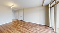 Located on the 16th floor at 1215 East West Highway in Silver Spring, MD, this one-bedroom, two-bathroom residence offers a well-designed open-concept layout with a bright and airy atmosphere. The living area features warm hardwood flooring that flows throughout, neutral-toned walls, and expansive floor-to-ceiling sliding glass doors that lead to a private balcony with sweeping views of the Silver Spring cityscape, allowing abundant natural light to fill the space.

The kitchen is thoughtfully laid out with light maple cabinetry, dark granite countertops, a breakfast bar peninsula, and black appliances including a gas range, built-in microwave, dishwasher, and refrigerator. Tile flooring and a skylight above add a functional and bright character to the cooking space.

The spacious primary bedroom features plush carpeting, a large window framing elevated city views, and access to a dedicated closet. Two full bathrooms serve the unit — one featuring a vanity with warm wood cabinetry, a large mirror with overhead lighting, and tile flooring.

A dedicated entrance provides a smooth transition into the home. The overall design balances comfort and functionality, making this a well-appointed urban residence in the heart of Silver Spring.