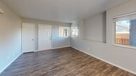Located at 941 Danrose Dr in American Canyon, California, this one-bedroom, two-bathroom single-story home offers a practical and comfortable layout. The open living room is a welcoming space featuring rich wood-look flooring, neutral gray walls, a ceiling fan with light fixture, and a corner window that draws in natural light and outdoor views. A built-in niche adds a subtle architectural detail to the living area. The galley-style kitchen is efficiently designed with white shaker cabinetry, granite-look countertops, wood-look flooring, and white appliances including a refrigerator, electric range, and dishwasher — all bathed in warm overhead lighting. The generously sized primary bedroom is finished with soft wall-to-wall carpeting and a large window that fills the room with natural light, creating a calm and restful atmosphere. Both bathrooms are clean and functional, featuring wood-look tile flooring, white vanities with stone-look countertops, and a full tub-shower combination. A hallway connects the living spaces to the private quarters, maintaining an efficient flow throughout the home. The overall aesthetic is clean and neutral, providing a move-in ready canvas throughout.