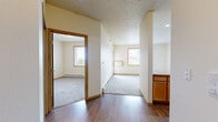 This well-appointed one-bedroom, one-bathroom unit in Fargo, North Dakota offers a practical and comfortable layout across a single floor. The open-concept kitchen is equipped with black appliances, including a refrigerator, range, and microwave, complemented by warm honey-toned cabinetry and laminate countertops. A peninsula-style counter separates the kitchen from the carpeted living area, creating a cohesive and functional shared space. Hardwood-style flooring runs through the kitchen and entry hallway, adding a touch of warmth and easy maintenance underfoot. The living area is bright and welcoming, with multiple windows dressed with blinds that invite natural light while maintaining privacy. A baseboard heating system ensures year-round comfort. The bedroom is a cozy retreat featuring plush carpeting, a large window with outdoor views, and a generously sized closet with bi-fold doors offering ample storage. The full bathroom includes a wide vanity with warm wood cabinetry, a large mirror with overhead lighting, and a full soaking tub and shower combination, set on durable tile flooring. A dedicated laundry room with in-unit washer and dryer and built-in wire shelving adds exceptional convenience. The textured ceilings and neutral color palette throughout lend the space a clean, move-in-ready appeal.