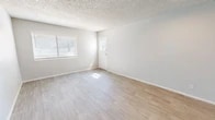 Located at 4400 Montgomery Blvd NE in Albuquerque, New Mexico, this well-appointed single-floor unit offers a thoughtfully organized layout comprising a combined kitchen and living room, one bedroom, one bathroom, a hallway, and two closets. The living area is finished with light-toned luxury vinyl plank flooring that extends throughout, complemented by crisp white trim, neutral gray walls, and a textured ceiling. Natural light filters in generously through horizontal-blind-fitted windows, creating a bright and airy atmosphere. The front entry opens directly into the spacious living room, which offers a clean, open canvas for a variety of furniture arrangements. The kitchen is a standout feature, boasting white upper cabinetry, gray lower cabinets, light countertops, and a full suite of stainless steel appliances including a refrigerator and gas range. A flush-mount ceiling fixture provides ample task lighting. The bedroom is carpeted for comfort and includes a window for natural light, offering a cozy and functional retreat. Two closets provide practical storage throughout the unit. The bathroom is finished cleanly with a full tub and shower combination. The overall aesthetic is modern, clean, and move-in ready.