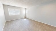 Located at 4400 Montgomery Blvd NE in Albuquerque, New Mexico, this well-appointed single-floor unit offers a thoughtfully organized layout comprising a combined kitchen and living room, one bedroom, one bathroom, a hallway, and two closets. The living area is finished with light-toned luxury vinyl plank flooring that extends throughout, complemented by crisp white trim, neutral gray walls, and a textured ceiling. Natural light filters in generously through horizontal-blind-fitted windows, creating a bright and airy atmosphere. The front entry opens directly into the spacious living room, which offers a clean, open canvas for a variety of furniture arrangements. The kitchen is a standout feature, boasting white upper cabinetry, gray lower cabinets, light countertops, and a full suite of stainless steel appliances including a refrigerator and gas range. A flush-mount ceiling fixture provides ample task lighting. The bedroom is carpeted for comfort and includes a window for natural light, offering a cozy and functional retreat. Two closets provide practical storage throughout the unit. The bathroom is finished cleanly with a full tub and shower combination. The overall aesthetic is modern, clean, and move-in ready.