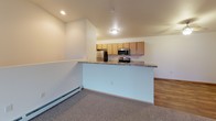 Located at 900 Rock Ridge Ct in Merrill, Wisconsin, this single-floor unit offers a practical and comfortable layout designed for everyday living. The open-concept living and kitchen area is a central highlight, where a peninsula with granite-style countertops visually separates the two spaces while maintaining an airy, connected feel. The kitchen is well-equipped with stainless steel appliances — including a refrigerator, electric range, microwave, and dishwasher — complemented by warm honey-toned wood cabinetry and durable hardwood-style flooring. The living area features soft carpeting, a ceiling fan with light fixture, and baseboard heating, creating a cozy and functional space. The bedrooms are generously sized, each with plush carpet, ceiling fans, natural light from windows with blinds, and baseboard heating for comfort throughout the seasons. The bathroom is outfitted with a granite-top vanity with wood cabinetry, a large mirror with overhead lighting, hardwood-style flooring, and a clean white walk-in shower unit with chrome fixtures. Throughout the unit, neutral tones and clean finishes provide a welcoming, move-in-ready atmosphere.
