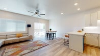 This single-floor residence is thoughtfully designed with a clean, modern aesthetic and a neutral palette that creates a bright, cohesive atmosphere throughout. The open-concept living and kitchen area serves as the heart of the space, where light wood-style flooring flows seamlessly underfoot. The living room is generously proportioned, featuring recessed lighting, a ceiling fan, and a sliding glass door that opens directly onto a private balcony, flooding the room with natural light and providing outdoor views. An additional window with blinds further enhances the brightness of the space.

The kitchen is well-equipped and visually striking, showcasing white cabinetry with sleek hardware, white subway tile backsplash, white quartz countertops, and stainless steel appliances including a range and over-the-range microwave. A peninsula with bar seating adds a functional and social dining element to the layout.

The bedroom features plush carpeting, a ceiling fan, and a window with blinds, offering a comfortable and quiet retreat. Two bathrooms serve the unit: one featuring a glass-enclosed walk-in shower with large-format tile, and the other offering a full tub-shower combination with matching tile surround. Both bathrooms are finished with white vanities, quartz countertops, and wood-style flooring, maintaining the modern character found throughout the residence.