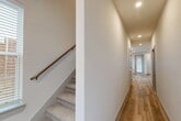 Located at 4515 Bluebonnet Ln in Melissa, TX, this two-story home offers a clean, modern aesthetic across two thoughtfully organized floors. The main level serves as the heart of the home, anchored by an open-concept living, dining, and kitchen area. The kitchen is outfitted with crisp white cabinetry, stainless steel appliances including a refrigerator, microwave, and range, and a large island with a quartz countertop and matte black fixtures — a striking contrast against the light hardwood-style flooring found throughout the main level. An attached garage with an automatic opener provides convenient access. The second floor houses two bedrooms, each with plush carpeting, and the primary bedroom includes a generous walk-in closet with built-in shelving and hanging rods. A bonus room on the upper level adds flexible living space, brightened by multiple windows with natural light. Four bathrooms are distributed across both floors, including a well-appointed bath featuring large-format tile, a soaking tub, and matte black hardware. A dedicated laundry area and two hallways with recessed lighting complete the layout, offering a functional and cohesive living experience throughout.