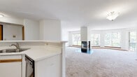 Located at 9900 Briar Rd in Bloomington, MN, this one-bedroom, two-bathroom residence offers a thoughtfully arranged single-floor layout. The expansive living room is a true centerpiece, anchored by a striking freestanding glass fireplace that serves as a visual divider between the living and dining areas. Large windows on multiple walls flood the space with natural light and frame pleasant outdoor views of the surrounding greenery, while a sliding glass door opens directly onto a private balcony. Soft carpeting throughout the living areas adds warmth underfoot.

The kitchen features white cabinetry with wood-trimmed accents, ample upper and lower storage, a double stainless steel sink, and a range, all finished with light tile flooring. A half-wall partition visually separates the kitchen from the living area while maintaining an open feel.

The generously sized primary bedroom offers carpeted flooring, a large window for natural light, and dedicated closet space. Two bathrooms serve the home — one featuring a tub/shower combination and tile flooring, and the other a vanity with under-sink storage and a mirrored medicine cabinet. Connected hallways provide a logical flow between all rooms, completing this well-organized and comfortable Bloomington residence.