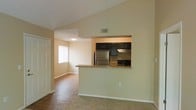 This two-story residence offers a thoughtfully designed interior that blends functionality with a warm, inviting aesthetic. The main living area is anchored by a pass-through kitchen, which features dark espresso cabinetry contrasting cleanly against light-colored walls. Stainless steel appliances, including a full-size refrigerator and a range with overhead ventilation, outfit the kitchen efficiently. The pass-through counter provides a casual bar-style surface, creating a seamless visual and functional connection between the kitchen and the adjacent living space.

The flooring transitions from warm hardwood in the main living and dining areas to plush carpet in the lounge space, offering both practicality and comfort underfoot. Neutral, beige-toned walls throughout contribute to a bright and cohesive atmosphere. A window in the adjoining room allows natural light to filter in, enhancing the open feel of the connected spaces. Vaulted or angled ceiling lines add visual height and dimension to the interior. White panel doors and clean baseboards complete the well-maintained, move-in-ready presentation of this multi-level residence.