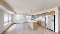 Located at 2536 Rice St in Little Canada, MN, this well-appointed 3-bedroom, 2-bathroom residence offers a thoughtfully designed single-floor layout. The open-concept kitchen and living area serves as the heart of the home, featuring warm-toned cabinetry, white quartz countertops, a large center island with pendant lighting, and a full suite of stainless steel appliances including a range, microwave, dishwasher, and refrigerator. Light wood-style flooring runs throughout the main living spaces, complemented by large windows with vertical blinds that invite generous natural light and outdoor views of the surrounding greenery.

The spacious living room continues the bright, airy aesthetic with clean neutral walls and light flooring. The primary bedroom is generously sized, complete with a ceiling fan, large window, and plush carpeting. The additional bedrooms also feature soft carpet and ample natural light. Two closets provide convenient storage throughout the unit.

The bathrooms are finished with wood-look flooring and clean, modern fixtures. The full bathroom includes a soaking tub with a curved shower rod and glass enclosure, while the second bathroom features a double-sink vanity with warm wood cabinetry, a white countertop, and a large mirror. The overall aesthetic is clean, modern, and move-in ready.