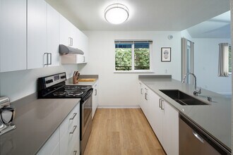 Renovated Package I kitchen with stainless steel appliances, white cabinetry, grey quartz countertops, and hard surface flooring - eaves Redmond Campus