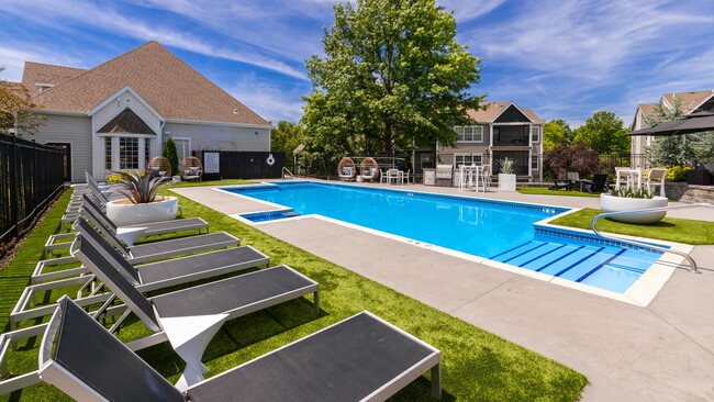 Enjoy a sunny day by the pool featuring comfortable lounge chairs, stylish seating, and a beautifully landscaped setting perfect for relaxation. - Market 1900 Apartment Homes