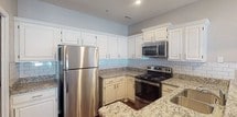 This single-floor residence offers a thoughtfully designed layout that balances comfort and functionality throughout. The living area is spacious and inviting, featuring soft wall-to-wall carpeting, crown molding, a ceiling fan, and a textured ceiling. Natural light streams in through large windows, creating a bright and airy atmosphere. The space opens into an adjacent area with track lighting, providing flexibility for dining or additional lounging.

The kitchen is a standout feature, showcasing granite countertops, crisp white cabinetry with raised-panel detailing, a light blue subway tile backsplash, and stainless steel appliances including an electric range and over-the-range microwave. A convenient pass-through counter connects the kitchen to the living area, enhancing the open feel.

The bedrooms are comfortably sized with plush carpeting, neutral toned walls, and windows that bring in natural views of the surrounding greenery. A closet is accessible from the main living corridor, offering practical storage.

Two full bathrooms serve the residence. The primary bathroom features a wide vanity with dual sinks, a large mirror, and a bright Hollywood-style light bar. The secondary bathroom includes a shower-tub combination, a single vanity with a mirror, and warm lighting. Both bathrooms are finished with hardwood-style flooring, adding a clean, polished look throughout.