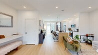 Located in Frisco, TX, this contemporary two-story home offers a thoughtfully designed layout spread across two well-proportioned floors. The main level opens into a bright living room with recessed lighting, light wood flooring, and a large window that fills the space with natural light. The open-concept kitchen is a standout feature, boasting white shaker cabinetry, a subway tile backsplash, stainless steel appliances, and a center island with a white quartz countertop and pendant lighting overhead. A welcoming hallway with a built-in console table and mirror provides a clean entryway transition. Three full bathrooms serve the home, including a primary bath with a double-sink vanity, white cabinetry, and a glass-enclosed walk-in shower with tile surround. The primary bedroom is a comfortable retreat with natural light and access to a walk-in closet featuring wire shelving systems. Additional bedrooms are well-sized with ceiling fans and ample natural light. A private balcony extends the living space outdoors, while two staircases connect the floors efficiently. Light wood flooring runs throughout, contributing to the home's clean, modern aesthetic. The overall ambiance is bright, airy, and move-in ready.