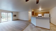 Located at 3900 Doolittle Drive in Stevens Point, Wisconsin, this single-floor unit offers a practical and well-organized layout suited for comfortable everyday living. The open-concept living and dining area is finished with neutral carpet and features a ceiling fan overhead, a wall-mounted air conditioning unit, and a sliding glass door that fills the space with natural light while providing direct access to outdoor greenery.

The kitchen is positioned adjacent to the living area and separated by a peninsula counter with granite-style countertops, offering a natural divide between spaces. Warm-toned wood cabinetry provides ample storage, and the kitchen is equipped with an electric range, dishwasher, and an under-cabinet range hood. Tile flooring runs throughout the kitchen area.

The bedrooms are carpeted and generously sized, each featuring windows that frame outdoor views of surrounding trees and green space. The bathrooms include tile flooring, wood-toned vanity cabinetry with granite-style countertops, and full tub-shower combinations.

A dedicated laundry room houses a full-sized washer and dryer alongside wire shelving for additional storage, completing the unit's functional amenities.