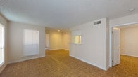 This single-story residence showcases a consistent design language throughout, highlighted by warm parquet wood flooring that extends across the living areas, bedrooms, and into the kitchen. The open living room serves as a central gathering space, anchored by a black fireplace surround and flanked by multiple windows fitted with horizontal blinds that allow for controlled natural light. A textured popcorn ceiling is present throughout the unit.

A pass-through window connects the living area to the galley-style kitchen, which features white cabinetry, a coil-element electric range, a full-size refrigerator, and a countertop sink. The layout is efficient and well-organized, with ample upper and lower cabinet storage.

The floor plan, visible in the 3D overview, reveals a logical flow between the living space, kitchen, and private areas. The bedroom offers a quiet retreat with a window for natural light and direct access to the bathroom. The bathroom includes a white vanity with built-in drawers, a large mirror, and a full tub-shower combination with white tile surround. Ceiling-mounted HVAC vents are present throughout, ensuring consistent climate control across the entire unit.