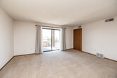 Located at 1270 Edgewood Rd NW in Cedar Rapids, Iowa, this two-bedroom, one-bathroom unit offers a practical and comfortable single-floor layout with a clean, neutral aesthetic throughout. The spacious living room is highlighted by plush wall-to-wall carpeting, a textured ceiling, and a sliding glass door that opens to a private balcony, filling the room with natural light and providing pleasant outdoor views. Warm wood-toned interior doors and trim add a consistent design accent across the space. The galley-style kitchen is well-appointed with honey-toned wood cabinetry, light laminate countertops, hardwood-style flooring, and stainless steel appliances including a range, refrigerator, and dishwasher. The primary bedroom is generously sized, featuring a reach-in closet with sliding wood doors, a window with outdoor views, and soft carpeting. The second bedroom is more compact yet comfortable, also carpeted and naturally lit. The full bathroom offers a long wood vanity with ample cabinet storage, a white countertop, a large wall mirror, and a tub-shower combination enclosed by frosted sliding glass doors, all set on warm tile flooring. This unit delivers a functional and well-maintained living environment in a residential Cedar Rapids neighborhood.