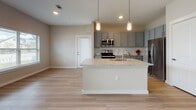 This single-floor residence is designed with a clean, contemporary aesthetic highlighted by a cohesive neutral color palette and quality finishes throughout. The open-concept living and kitchen area serves as the heart of the home, where light wood-style flooring extends across the space, and dual windows allow natural light to pour in, offering outdoor views. A ceiling fan overhead adds both function and comfort to the living area.

The kitchen is well-appointed with gray shaker-style cabinetry, a subway tile backsplash, stainless steel appliances including a range, microwave, and refrigerator, and a large granite-topped island with an undermount sink. Pendant lighting above the island adds a polished touch.

The bedroom is carpeted for comfort and features a ceiling fan, a natural light-admitting window, and two generously sized closets with double-panel doors and built-in shelving rods. An en-suite bathroom is finished with granite countertops, gray cabinetry, wood-look flooring, and a shower enclosure.

A secondary bathroom includes a full tub-shower combo with tile surround, granite vanity, and matching wood-look flooring. Throughout the space, consistent trim, neutral walls, and brushed nickel fixtures contribute to a cohesive and move-in-ready environment.