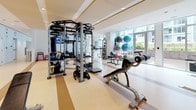 Located at 800 P Street NW in Washington, D.C., this professional-grade fitness center is a well-appointed, single-floor facility designed to support a comprehensive range of workout routines. The space is bathed in natural light streaming through large floor-to-ceiling windows, offering views of the surrounding urban landscape and creating an open, energizing atmosphere. Recessed ceiling lighting further enhances the bright, clean aesthetic throughout.

The cardio zone features an extensive row of treadmills equipped with individual screens, alongside stationary bikes, providing ample options for aerobic training. Full-length mirrors line the walls, amplifying the sense of space and allowing users to monitor their form during exercise.

The strength training area is equally well-stocked, with multiple cable machine stations, Smith machines, power racks, and a comprehensive dumbbell rack spanning a wide weight range. Adjustable benches are positioned throughout for versatile use. A dedicated functional training zone houses Life Fitness multi-functional rigs, medicine balls, stability balls, kettlebells, and other accessories, catering to dynamic and sport-specific workouts.

The flooring consists of durable, light-toned fitness flooring with accent striping, contributing to the clean and organized layout. Storage lockers are visible along one wall, adding practical convenience. The overall design is modern, efficient, and thoughtfully arranged to accommodate multiple users simultaneously.