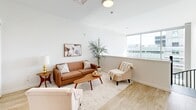 Located at 835 Hamilton Street in Allentown, PA, this contemporary two-floor residence offers a well-designed layout spread across two thoughtfully proportioned levels. The main floor showcases a striking open-concept kitchen and living area flooded with natural light from dramatic floor-to-ceiling windows. The kitchen is appointed with white shaker cabinetry, quartz countertops, stainless steel appliances, a subway tile backsplash, and a central island with bar seating — ideal for both cooking and casual dining. A separate dining area and an open living room complete the main floor, with light wood flooring running throughout.

The upper level houses the private quarters, including well-appointed bedrooms featuring light wood floors, clean white walls, and wall-mounted televisions. One bedroom opens directly to a private outdoor balcony with urban views. A dedicated office space provides a quiet, functional area with room for a full desk setup. The bathrooms are finished with white shaker vanities, quartz countertops, brushed nickel fixtures, and wood-look tile flooring. A spiral staircase serves as a distinctive architectural feature connecting the two floors. The overall aesthetic is clean, bright, and modern throughout.