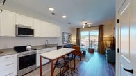 Located at 87 Union St in New Haven, CT, this thoughtfully designed residence offers a single-floor open-concept layout that seamlessly connects the kitchen, dining, and living areas. The kitchen is outfitted with crisp white shaker cabinetry extending to the ceiling, stainless steel appliances including a refrigerator, range, and built-in microwave, and a sleek countertop island with bar seating — ideal for casual dining and entertaining. Light wood-style flooring runs throughout, enhancing the bright, airy atmosphere created by recessed lighting and contemporary fixtures. The living area is generously proportioned, anchored by a modern globe chandelier, and flows directly through large sliding glass doors onto a private balcony with open urban views of the New Haven skyline. The bedroom is a serene retreat featuring dual windows that invite abundant natural light and neighborhood views, along with a well-sized closet. A full bathroom off the hallway is finished with a white vanity, large-format tile flooring, and a lighted mirror. A stacked in-unit laundry is also conveniently located in the hallway. Clean lines, neutral tones, and modern hardware throughout give this residence a polished, move-in-ready character.