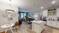 This well-appointed single-floor residence features a thoughtfully designed open-concept layout that seamlessly connects the kitchen, dining, and living areas. The kitchen is a standout, showcasing white shaker cabinetry, granite countertops, a subway tile backsplash, stainless steel appliances, and a central island illuminated by brushed nickel pendant lights. Wood-look flooring flows throughout the main living areas, enhancing the bright, cohesive aesthetic.

The living room is generously sized, featuring a ceiling fan, large windows with ample natural light, and access to an outdoor area. A dedicated dining nook sits adjacent to the kitchen, complete with its own pendant light fixture.

The primary bedroom offers a comfortable retreat with soft carpeting and a large window. Its en-suite bathroom includes a dual-sink vanity with granite countertops, white cabinetry, a large mirror, and a glass-enclosed shower. A second bedroom features large windows with outdoor views and plush carpeting. A second bathroom provides a vanity with granite countertops and a tub-shower combination. An in-unit laundry area adds everyday convenience to this polished, modern residence.