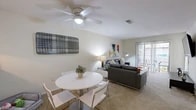 Located at 2777 SW Archer Rd in Gainesville, Florida, this single-floor unit offers a well-organized and functional layout designed for comfortable everyday living. The galley-style kitchen is lined with ample white cabinetry, a double-basin sink, a full suite of white appliances, and tile flooring, connecting to the dining and living areas through a convenient pass-through counter that enhances the open feel. The combined living and dining space features plush carpeting, a ceiling fan, and large sliding glass doors that flood the room with natural light and open directly onto a private outdoor patio. Two generously sized bedrooms each include ceiling fans, carpeted floors, and closet storage. The primary bedroom benefits from an expansive walk-in closet with wire shelving spanning multiple walls. The full bathroom is outfitted with a tub-shower combination and tile flooring. A dedicated laundry area near the entry houses a stacked washer and dryer unit, adding everyday convenience. Throughout the unit, neutral tones and consistent finishes create a cohesive, bright atmosphere well-suited for a variety of lifestyles.