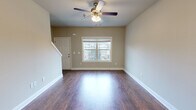 Located at 232 Epps Bridge Rd in Athens, GA, this two-story home offers five bedrooms and three bathrooms spread across two well-proportioned floors. The main level features an open-concept living room with rich hardwood-style flooring, a ceiling fan with light fixture, and a front-facing window that brings in natural light. The living area flows seamlessly toward the staircase and into the kitchen, which is a standout feature of the main floor. The kitchen is equipped with dark wood cabinetry, black appliances, recessed lighting, a pendant chandelier, and a large granite-topped island with a built-in sink — ideal for both cooking and gathering. The upper level houses the bedrooms, including a generously sized primary bedroom with a ceiling fan, a closet, and a window overlooking greenery. Additional bedrooms are carpeted, neutrally painted, and well-lit, offering comfortable and functional spaces. The bathrooms are consistently finished with granite vanity countertops, dark wood cabinetry, and tub-shower combinations. Throughout both floors, neutral warm-toned walls, white trim, and consistent flooring choices create a cohesive and clean aesthetic. Carpeted stairs connect the two levels, contributing to the home's practical and comfortable character.