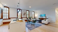 Located at 13125 Watertown Plank Road in Elm Grove, Wisconsin, this stunning single-floor residence masterfully combines historic architectural charm with contemporary design. Signature arched windows with rich wood trim flood the interior with natural light, creating a warm and inviting ambiance throughout.

The heart of the home is a spacious open-concept living, dining, and kitchen area. The modern kitchen features white cabinetry, stainless steel appliances including a French door refrigerator and wall oven, a sleek range hood, and a generous island with pendant lighting — perfect for both cooking and entertaining. The living and dining areas flow seamlessly, showcasing light hardwood flooring and large arched windows that frame lush outdoor views.

The primary bedroom offers a generous retreat, complemented by well-organized walk-in closets featuring custom built-in shelving and hanging storage. Four full bathrooms are elegantly appointed with white vanities, clean-lined cabinetry, and arched windows that maintain the building's historic character. A dedicated office provides a quiet workspace bathed in natural light. Additional conveniences include a laundry room, a hallway connecting the private quarters, and an impressive eight closets offering abundant storage throughout this distinctive and refined residence.