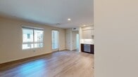 Located in Riverside, CA, North Grove A1D is a well-appointed 610-square-foot, one-bedroom, one-bathroom apartment designed with modern aesthetics and functional living in mind. The open-concept kitchen is a standout feature, showcasing two-tone cabinetry with warm wood-grain lower cabinets and light upper cabinets, a marble-style tile backsplash, quartz countertops, and a full suite of stainless steel appliances including a refrigerator, range, microwave, and dishwasher. Light wood-style flooring flows throughout the kitchen and main living areas, enhancing the bright, contemporary feel. The 120-square-foot bedroom features plush carpeting and a large window that fills the room with natural light and offers views of the surrounding community. A walk-in closet with built-in wire shelving provides ample storage. The bathroom is finished with light wood-style flooring, a wood-tone vanity with an undermount sink, a large mirror, and a full bathtub with shower. A hallway connects the main living areas efficiently. The unit also includes access to a balcony with open views of the modern multi-story residential complex. Recessed lighting throughout adds a polished, contemporary touch to this well-designed Riverside apartment.