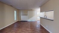 Located at 660 Halton Rd in Greenville, South Carolina, this single-floor residence offers a well-organized layout with a variety of functional living spaces. The galley-style kitchen is equipped with stainless steel appliances, including a refrigerator, range, and over-the-range microwave, complemented by rich dark cabinetry and granite countertops. Hardwood-style flooring runs throughout the kitchen and main living areas, adding warmth and continuity to the space. The open living area features sliding glass doors with vertical blinds, allowing natural light to filter in through multiple windows that frame views of surrounding greenery. Several bedrooms are carpeted for comfort, each with neutral-toned walls and windows fitted with blinds for privacy and light control. A dedicated dining area features hardwood-style flooring, a flush-mount light fixture, and a window for natural light. The bathroom is appointed with a wide granite vanity, dark cabinetry with brushed nickel hardware, a large framed mirror, and louvered closet doors that contribute to an organized and polished finish. Textured ceilings are consistent throughout, and the overall neutral color palette creates a clean, versatile ambiance suitable for a range of interior styles.