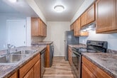 This single-floor, 2-bedroom, 1-bathroom residence offers a practical and comfortable layout with a clean, neutral aesthetic throughout. The open-concept living area greets you with warm hardwood-style flooring, a ceiling fan with light fixture, and a large window dressed with vertical blinds that invites natural light and garden views. This space flows seamlessly into the galley-style kitchen, which is appointed with warm wood cabinetry, granite-look countertops, and a full suite of appliances including a stainless steel refrigerator, electric range, dishwasher, and an in-unit washer. A double basin stainless steel sink completes the kitchen's functional design.

Both bedrooms feature plush carpeting and baseboard heating. The primary bedroom offers generous proportions with a ceiling fan, while the second bedroom includes a large reach-in closet with bifold doors and a window. Two hallways and additional closets provide ample storage throughout the unit. The bathroom is outfitted with wood-tone cabinetry, a white countertop vanity, and hardwood-style flooring. An entrance area and multiple closets contribute to an organized and efficient use of space throughout this well-appointed residence.