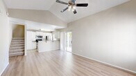 Located in Surprise, AZ, this two-story home offers four bedrooms and three bathrooms across two well-proportioned floors. The main floor is anchored by an open-concept living room and kitchen, where soaring vaulted ceilings and light wood-look flooring create a bright, airy atmosphere. A ceiling fan with integrated lighting adds both function and style to the living area, which connects seamlessly to the kitchen through a breakfast bar. The kitchen is outfitted with white cabinetry, granite-style countertops, stainless steel appliances including a refrigerator, range, and microwave, plus a double-basin sink positioned beneath a window that brings in natural light. Sliding glass doors off the main living area open to a gravel-landscaped backyard enclosed by block and wood fencing, offering privacy and a mature shade tree. Upstairs, the bedrooms feature neutral carpet, ceiling fans, and soft natural light. The bathrooms are finished with white vanities, granite-style countertops, and light hardwood-style flooring, with one bath featuring a tub-shower combo. A hallway, closet, and staircase round out the layout, providing practical storage and circulation throughout the home.