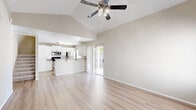 Located in Surprise, AZ, this two-story home offers four bedrooms and three bathrooms across two well-proportioned floors. The main floor is anchored by an open-concept living room and kitchen, where soaring vaulted ceilings and light wood-look flooring create a bright, airy atmosphere. A ceiling fan with integrated lighting adds both function and style to the living area, which connects seamlessly to the kitchen through a breakfast bar. The kitchen is outfitted with white cabinetry, granite-style countertops, stainless steel appliances including a refrigerator, range, and microwave, plus a double-basin sink positioned beneath a window that brings in natural light. Sliding glass doors off the main living area open to a gravel-landscaped backyard enclosed by block and wood fencing, offering privacy and a mature shade tree. Upstairs, the bedrooms feature neutral carpet, ceiling fans, and soft natural light. The bathrooms are finished with white vanities, granite-style countertops, and light hardwood-style flooring, with one bath featuring a tub-shower combo. A hallway, closet, and staircase round out the layout, providing practical storage and circulation throughout the home.