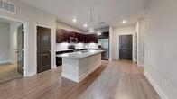 This 1,070-square-foot, single-story residence at 13504 Citicards Way in Jacksonville, FL features 2 bedrooms, 2 bathrooms, and 2 closets thoughtfully arranged for comfortable living. The open-concept kitchen and living area serves as the heart of the home, showcasing rich dark espresso cabinetry, a marble-style tile backsplash, granite countertops, stainless steel appliances, and a large center island with pendant lighting — ideal for cooking and entertaining. Light wood-style flooring flows throughout the main living areas, complemented by neutral wall tones that create a bright, welcoming ambiance. The living room provides direct access to the exterior and benefits from natural light through windows with blinds. Both bedrooms feature plush carpeting and ceiling fans, with the primary bedroom spanning 170 square feet and offering access to an en-suite bathroom. The primary bath is well-appointed with a dual-sink granite vanity, wood-tone cabinetry, a glass-enclosed walk-in shower with marble-style tile, and a separate soaking tub. The secondary bathroom mirrors the refined aesthetic with a tiled tub-shower combo and granite vanity. A walk-in closet with wire shelving provides ample storage.