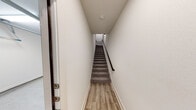 This well-designed two-story residence offers a thoughtful layout across two levels, blending modern finishes with functional living spaces. The ground level features an attached garage equipped with an automatic opener and fluorescent lighting, providing generous space for vehicles and storage. A dedicated entryway with light wood-look flooring and a carpeted staircase with a sleek dark metal handrail connects the levels seamlessly.

The main living floor showcases an open-concept design where the kitchen, dining, and living areas flow together naturally. The kitchen is outfitted with granite countertops, gray cabinetry with matte black hardware, a subway tile backsplash, and stainless steel appliances including an electric range and over-the-range microwave. A peninsula with pendant lighting adds both style and function. The spacious living area features light hardwood-style flooring, a ceiling fan, and French doors that invite natural light.

The bedrooms are carpeted and finished with clean white walls and paneled gray interior doors, conveying a calm, neutral aesthetic. The bathroom carries the same refined character, featuring granite countertops, gray cabinetry with black hardware, and a large mirror. Throughout the residence, white walls, consistent trim work, and cohesive finishes create a clean, move-in-ready environment.