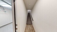 This well-designed two-story residence offers a thoughtful layout across two levels, blending modern finishes with functional living spaces. The ground level features an attached garage equipped with an automatic opener and fluorescent lighting, providing generous space for vehicles and storage. A dedicated entryway with light wood-look flooring and a carpeted staircase with a sleek dark metal handrail connects the levels seamlessly.

The main living floor showcases an open-concept design where the kitchen, dining, and living areas flow together naturally. The kitchen is outfitted with granite countertops, gray cabinetry with matte black hardware, a subway tile backsplash, and stainless steel appliances including an electric range and over-the-range microwave. A peninsula with pendant lighting adds both style and function. The spacious living area features light hardwood-style flooring, a ceiling fan, and French doors that invite natural light.

The bedrooms are carpeted and finished with clean white walls and paneled gray interior doors, conveying a calm, neutral aesthetic. The bathroom carries the same refined character, featuring granite countertops, gray cabinetry with black hardware, and a large mirror. Throughout the residence, white walls, consistent trim work, and cohesive finishes create a clean, move-in-ready environment.