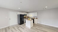 Located at 750 Bergen Rd in North Augusta, SC, this one-bedroom, one-bathroom single-floor residence offers a clean, modern layout designed for comfortable everyday living. Light gray walls and consistent light wood-look luxury vinyl flooring run throughout, creating a bright and cohesive aesthetic.

The open-concept kitchen and living area serves as the heart of the home. The kitchen is well-appointed with white shaker-style cabinetry, granite-look countertops, black appliances including a refrigerator, range, over-the-range microwave, and dishwasher, as well as a central island that provides additional prep space and storage. Recessed lighting illuminates the area efficiently.

The living room flows naturally from the kitchen and features French doors that open to a private patio, allowing natural light to fill the space and providing easy outdoor access. The bedroom is a comfortable size, featuring a window with exterior views and a dedicated closet. A second closet provides additional storage elsewhere in the unit.

The bathroom features a white vanity with an integrated sink, a large mirror with overhead lighting, and a combined tub and shower. The clean, neutral palette throughout the home ensures a move-in-ready feel. Two closets add practical storage to round out this efficiently designed residence.