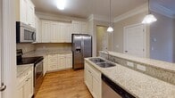 This single-floor residence offers a thoughtfully designed layout with a cohesive neutral color palette and a blend of hardwood and carpeted flooring throughout. The open-concept living and dining areas are defined by elegant crown molding, warm hardwood floors, and pendant lighting that creates a welcoming ambiance. Large windows invite natural light into the bedrooms, which feature plush carpeting and ceiling fans for comfort.

The kitchen is a functional highlight, equipped with crisp white cabinetry, granite countertops, and a full suite of stainless steel appliances including a refrigerator with ice maker, electric range, and microwave. A peninsula with a double sink and pendant lighting above adds both style and practicality, while hardwood flooring ties the space seamlessly to the main living areas.

The bathrooms are finished with granite-topped vanities, tile flooring, and clean white cabinetry. The primary bathroom includes a walk-in shower with sliding glass doors and a separate closet. A dedicated laundry room with a full-size washer and dryer, overhead cabinetry, and tile flooring adds everyday convenience. Overall, the space presents a clean, move-in-ready environment with consistent finishes and a practical, comfortable layout.
