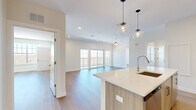 This well-appointed 2-bedroom, 2-bathroom residence in Brewster, NY offers a thoughtfully designed open-concept layout with modern finishes throughout. The combined kitchen and living area serves as the heart of the home, featuring warm wood-toned cabinetry, stainless steel appliances, a classic white subway tile backsplash, and a generous quartz-topped island with an undermount sink — all illuminated by striking globe pendant lights. The living room flows seamlessly from the kitchen and opens to a private balcony through large sliding glass doors, flooding the space with natural light and offering pleasant outdoor views. Hardwood flooring runs throughout the entire residence, adding warmth and continuity. The spacious primary bedroom features a large picture window with sweeping views of the surrounding hills and landscape, a walk-in closet with built-in wire shelving, and an en-suite bathroom with a wood-paneled floating vanity, quartz countertop, and a tiled walk-in shower. The second bedroom includes double shaker-style closet doors, while the second bathroom offers a soaking tub with full tile surround. Clean white walls, recessed lighting, and a neutral palette give the entire space a bright, contemporary ambiance.