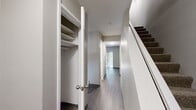 This three-bedroom, three-bathroom home spans three floors, offering a generous and well-distributed layout designed for comfortable living. The ground level provides a compact entry point, while the two upper floors each offer substantial living space, housing the primary rooms and amenities.

The kitchen is a standout feature, equipped with stainless steel appliances including a refrigerator, range, and dishwasher. Gray shaker-style cabinetry pairs with granite-look countertops and a peninsula, creating a functional and modern workspace. A window above the sink brings in natural light and views of the outdoors.

The living areas feature warm hardwood-style flooring and neutral gray-toned walls, lending a clean and contemporary feel throughout. Carpeted bedrooms offer a softer underfoot experience, each equipped with closets — including sliding mirrored closet doors in select rooms. The primary bedroom provides a comfortable, well-sized retreat with a window and built-in shelving in the closet.

All three bathrooms are finished with granite-top vanities and wood-style flooring. One bathroom includes a full tub-shower combo with white tile surround. A hallway with built-in shelving closet and staircase with carpet runners connect the floors seamlessly. A utility room and additional living room on a separate level round out this well-structured home.