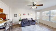 Located on West Franklin Street in Richmond, Virginia, this well-appointed one-bedroom, one-bathroom unit offers a thoughtfully organized layout across a single floor. The bright living room serves as the heart of the space, featuring crown molding, hardwood-style flooring, a ceiling fan with light fixture, and large windows with blinds that invite generous natural light. A wall-mounted flat-screen television adds a modern touch to this welcoming area. The kitchen connects to the living room via a charming pass-through opening with a breakfast bar and two counter-height chairs, making it ideal for casual dining. The kitchen is equipped with warm wood cabinetry and standard appliances. The bedroom offers a comfortable retreat with plush carpeting, a ceiling fan, and a window overlooking the exterior. It provides direct access to both a dedicated closet and the full bathroom. The bathroom features tile flooring, a tub/shower combination with tiled surround, and wood-toned cabinetry with ample storage. A dedicated laundry area and hallway round out the unit's practical floor plan. The overall ambiance is cozy and functional, with classic detailing throughout.