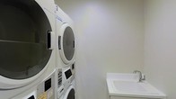 Located at 2 Hamilton Road in Morristown, New Jersey, this single-floor laundry facility is designed for functionality and ease of use. The space is finished with clean, neutral walls that contribute to a bright and tidy environment. The room is equipped with stacked washer and dryer units, maximizing the use of vertical space while keeping the floor area open and accessible. The machines feature digital control panels, offering a range of wash and dry cycle options to accommodate various laundry needs. Alongside the laundry units, a white utility sink with a faucet provides added convenience for hand-washing, pre-treating garments, or general cleaning tasks. The overall layout is straightforward and well-organized, ensuring a smooth and efficient laundry experience. The space reflects a practical design approach, prioritizing utility and cleanliness throughout.