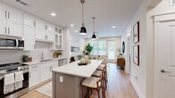 Located on Statesville Road in Huntersville, NC, this thoughtfully designed one-bedroom, two-bathroom residence combines modern aesthetics with practical functionality across a single, efficiently organized floor.

The open-concept kitchen and living area serves as the heart of the home. The kitchen is outfitted with floor-to-ceiling white shaker cabinetry accented by matte black hardware, stainless steel appliances, quartz countertops, an undermount sink, and a central island with seating — ideal for both meal prep and casual dining. Light wood-tone flooring and recessed lighting carry throughout, creating a warm, cohesive atmosphere.

The adjacent living room is bright and welcoming, featuring large windows with outdoor views and a ceiling fan overhead. The spacious primary bedroom includes ample natural light from oversized windows, a ceiling fan, and direct access to a walk-in closet with built-in shelving.

Both bathrooms are finished to a high standard. The primary bath features large-format tile in a walk-in glass-enclosed shower with a built-in bench, while the second bath includes a white vanity with quartz countertops and decorative tile flooring. Additional highlights include a dedicated laundry area, a functional entryway nook, and consistent light-toned finishes throughout that contribute to a clean, modern ambiance.